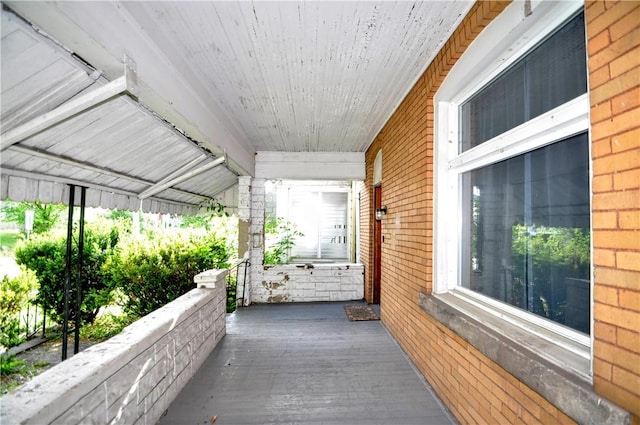 view of side of home featuring brick siding and covered porch