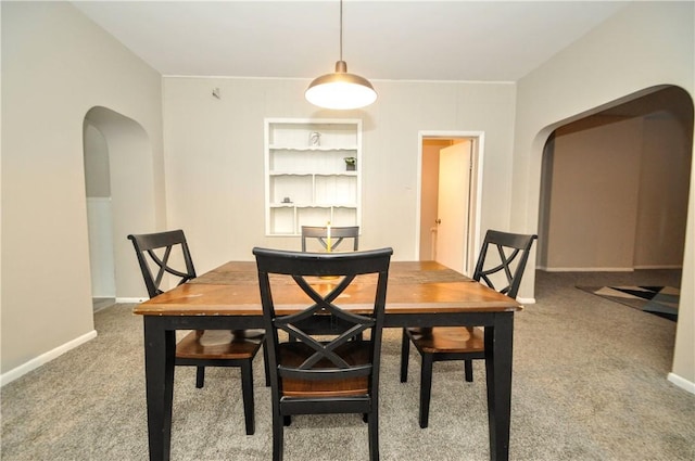 dining area featuring arched walkways, carpet, baseboards, and built in shelves