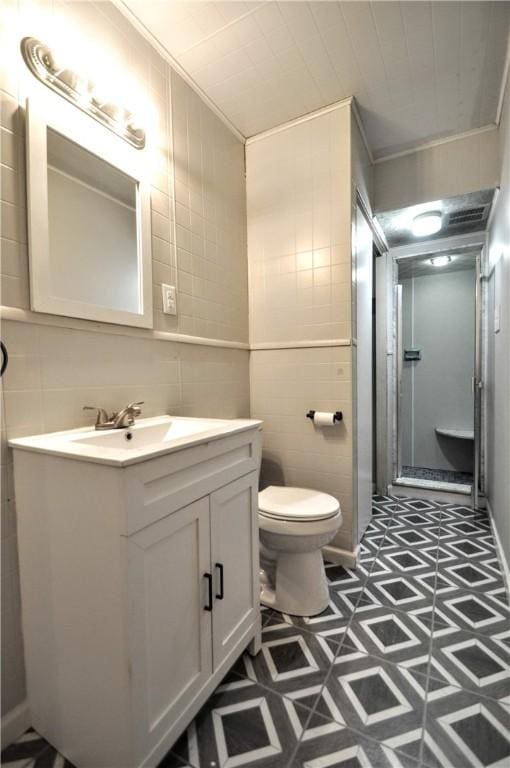 bathroom featuring tile walls, toilet, vanity, and crown molding