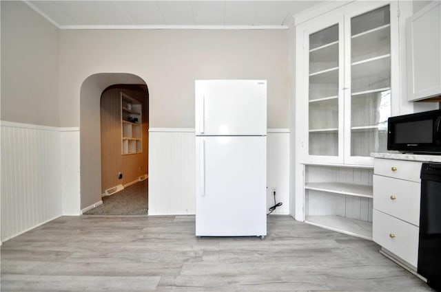 unfurnished dining area featuring wainscoting, crown molding, and light wood finished floors
