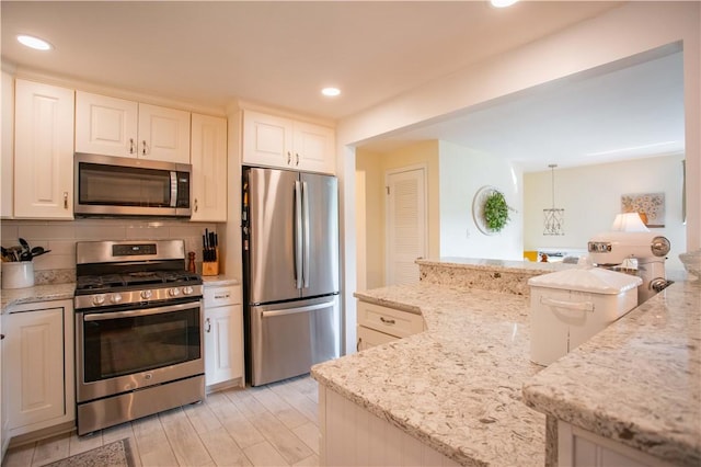 kitchen with stainless steel appliances, light stone counters, recessed lighting, decorative backsplash, and light wood finished floors