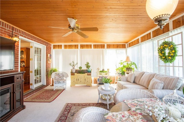 sunroom / solarium with ceiling fan, carpet, wooden ceiling, outdoor lounge area, and brick wall