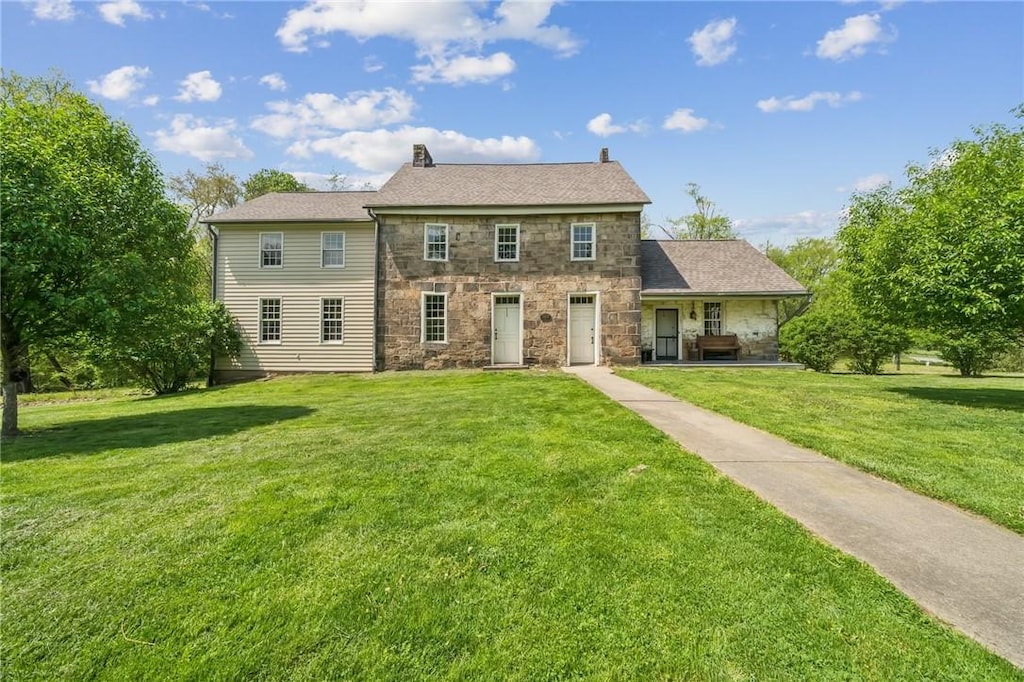 colonial house with stone siding and a front yard