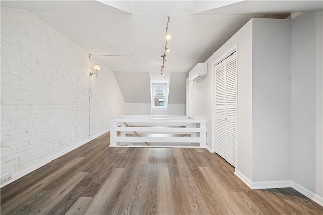 3474 Ligonier St, Lawrenceville, PA 15201 - additional living space with brick wall, a wall mounted air conditioner, wood finished floors, and baseboards