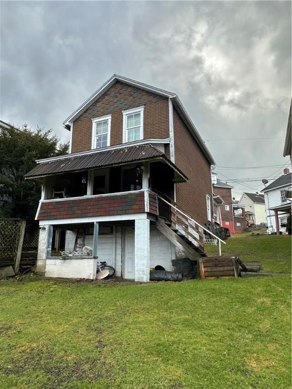 back of house featuring a lawn and brick siding