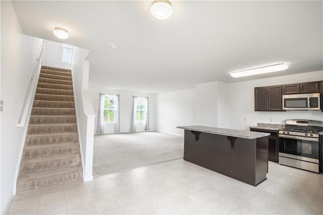 118 Leslie Farms Dr, Connoquenessing Boro, PA 16033 - kitchen featuring appliances with stainless steel finishes, a breakfast bar area, dark brown cabinets, light colored carpet, and open floor plan