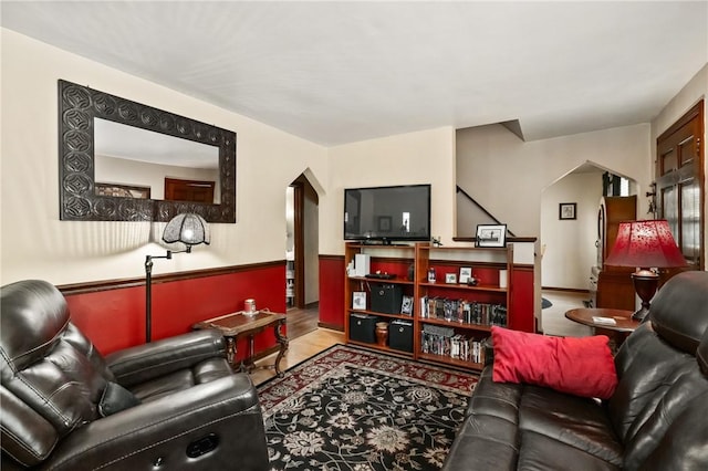 living area with arched walkways and wood finished floors