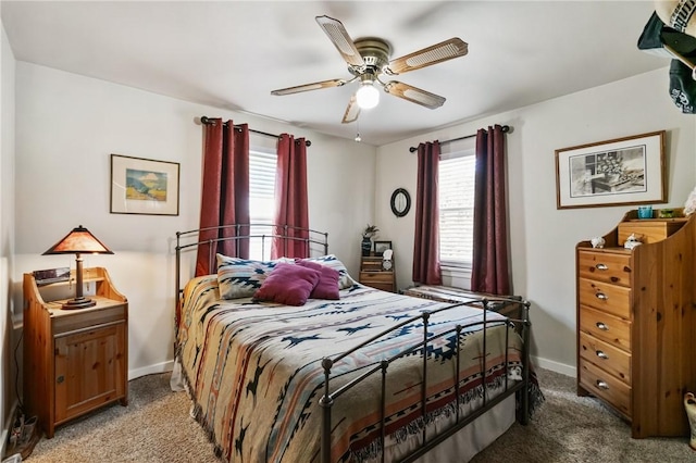 bedroom featuring light colored carpet, multiple windows, baseboards, and ceiling fan