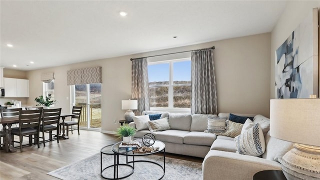 living area with healthy amount of natural light, light wood-style floors, recessed lighting, and baseboards