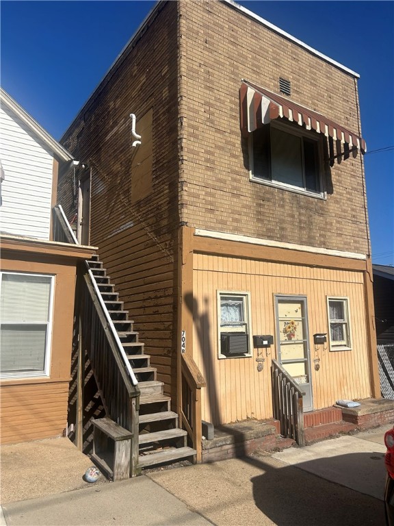 view of front facade with brick siding, stairway, and cooling unit