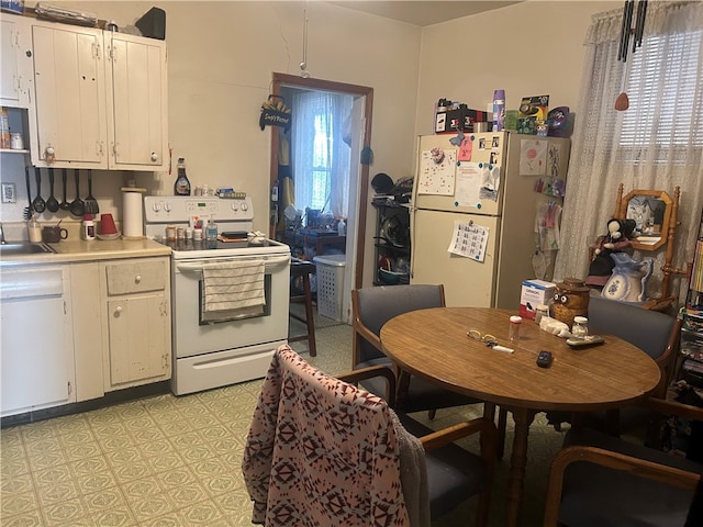 kitchen with white appliances, light countertops, white cabinets, and light flooring