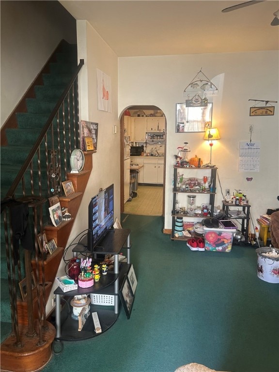carpeted living room featuring arched walkways and stairway