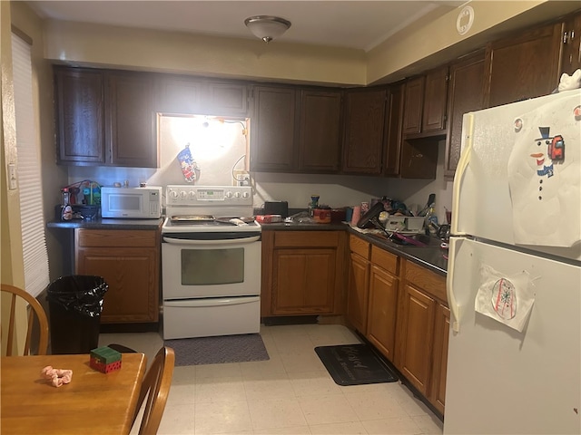 kitchen with white appliances, dark countertops, and light flooring