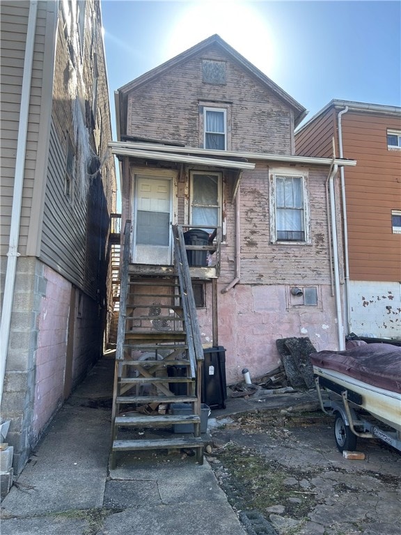 rear view of house featuring brick siding and stairs