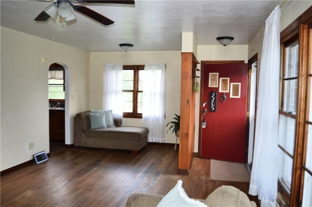 foyer with wood finished floors, ceiling fan, baseboards, and arched walkways