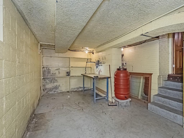 unfinished basement with concrete block wall and stairs