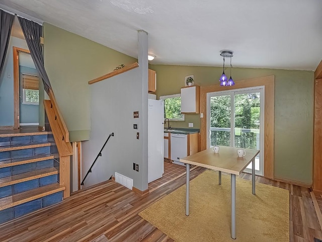 kitchen featuring white appliances, lofted ceiling, wood finished floors, and decorative light fixtures
