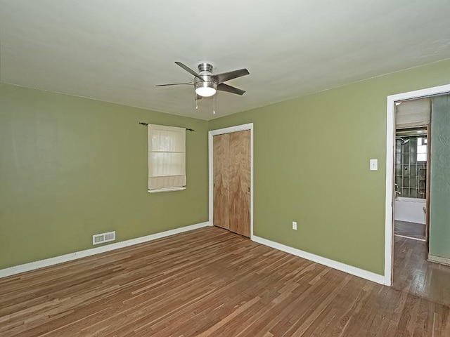 unfurnished bedroom with baseboards, wood finished floors, a closet, and a ceiling fan