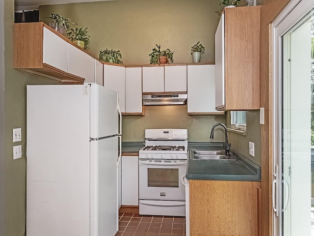 kitchen featuring white appliances, under cabinet range hood, white cabinetry, a sink, and dark tile patterned flooring