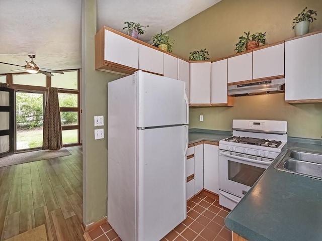 kitchen featuring white appliances, under cabinet range hood, white cabinets, a ceiling fan, and a sink