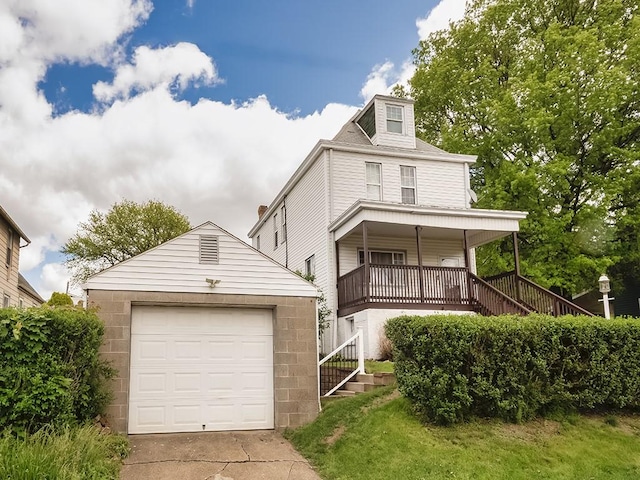 view of front of house with stairway, covered porch, a detached garage, and an outbuilding