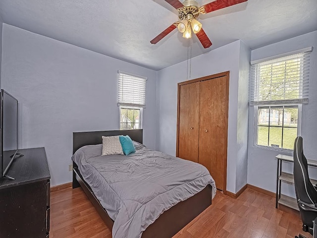 bedroom with wood finished floors, a closet, baseboards, and ceiling fan