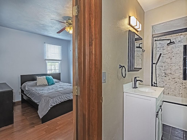 bedroom featuring a sink, wood finished floors, and a textured wall