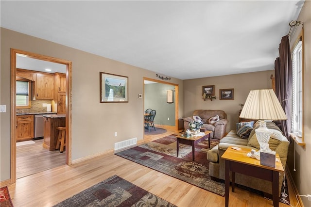 living room featuring light wood finished floors, healthy amount of natural light, and baseboards