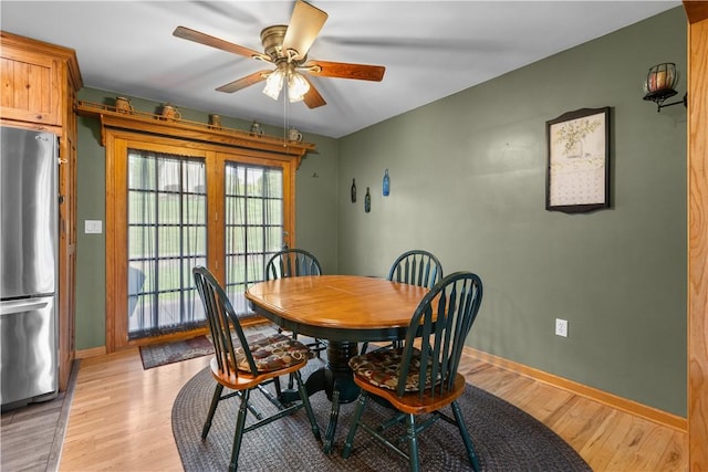 dining space with a ceiling fan, light wood-style flooring, and baseboards