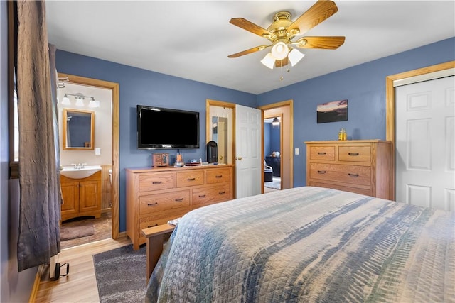 bedroom with a sink, light wood finished floors, ceiling fan, and connected bathroom