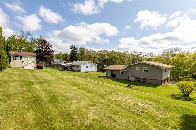 view of green lawn featuring a storage shed, an outbuilding, and view of wooded area