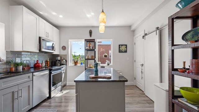 2132 Sarah St Unit 201, South Side, PA 15203 - kitchen with appliances with stainless steel finishes, a sink, a center island, dark stone countertops, and backsplash