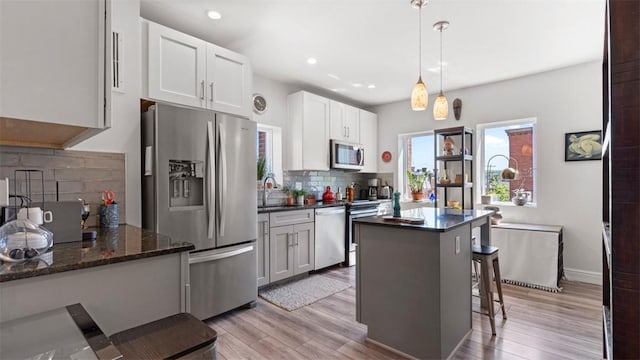 2132 Sarah St Unit 201, South Side, PA 15203 - kitchen featuring stainless steel appliances, a sink, backsplash, a center island, and light wood-style flooring