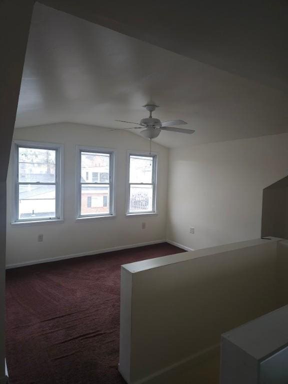 bonus room featuring vaulted ceiling, dark carpet, baseboards, and a ceiling fan