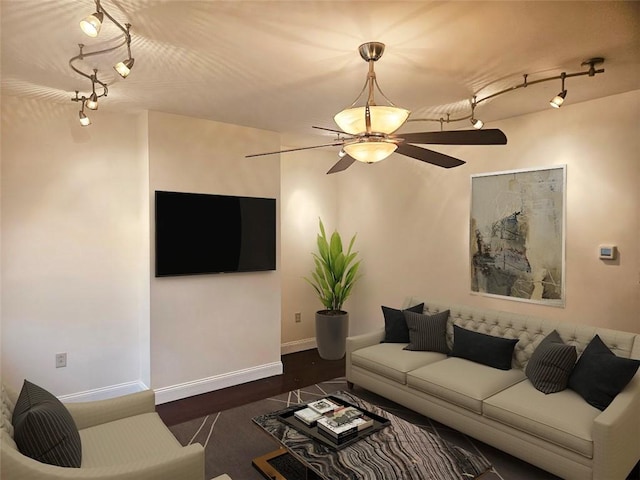 living room featuring track lighting, a ceiling fan, baseboards, and dark wood-type flooring