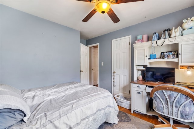 bedroom featuring wood finished floors, a ceiling fan, and a desk