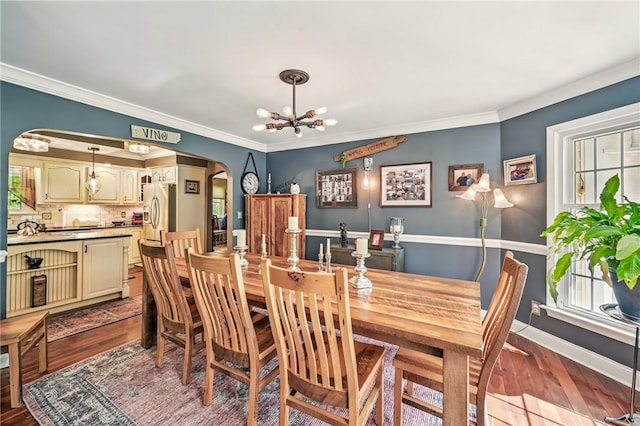 9935 Greiser Rd, Conneaut Lake Cra, PA 16316 - dining space with arched walkways, a chandelier, wood finished floors, crown molding, and baseboards