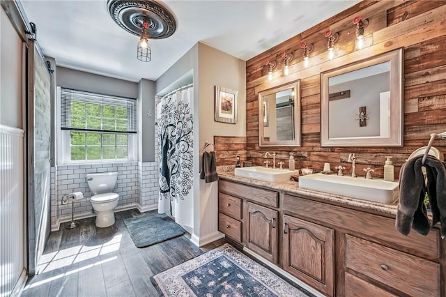 9935 Greiser Rd, Conneaut Lake Cra, PA 16316 - full bath featuring tile walls, wainscoting, toilet, wood finished floors, and double vanity