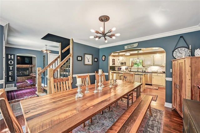 9935 Greiser Rd, Conneaut Lake Cra, PA 16316 - dining room with arched walkways, a fireplace, a chandelier, wood finished floors, and stairway
