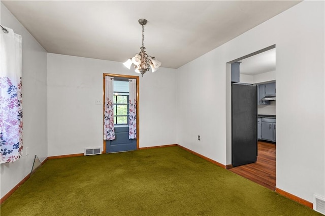 unfurnished dining area with carpet flooring, a chandelier, and baseboards
