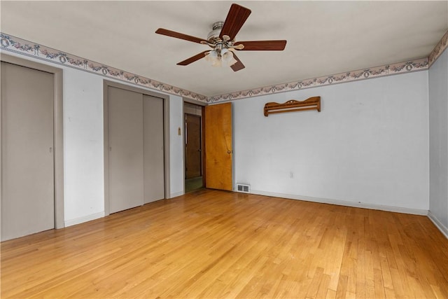 unfurnished bedroom featuring light wood-style flooring, multiple closets, a ceiling fan, and baseboards