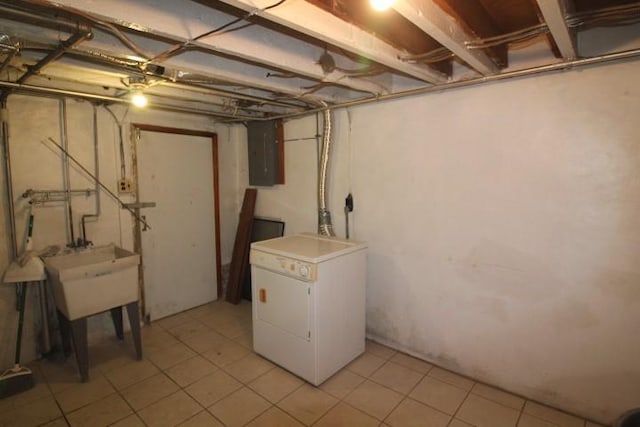 unfinished below grade area with washer / clothes dryer, a sink, and light tile patterned floors