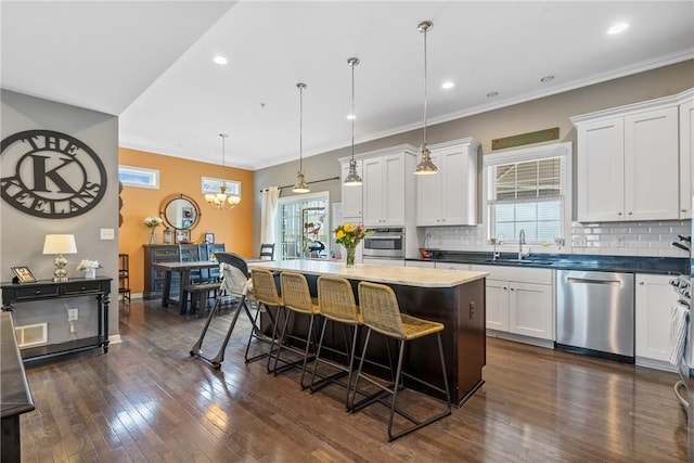 234 College Ave, Oakmont, PA 15139 - kitchen featuring stainless steel appliances, a sink, a breakfast bar, decorative backsplash, and crown molding