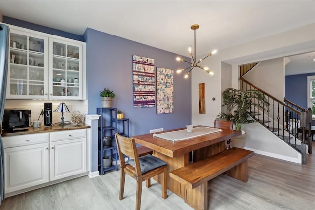 dining space featuring light wood finished floors, a chandelier, and stairway