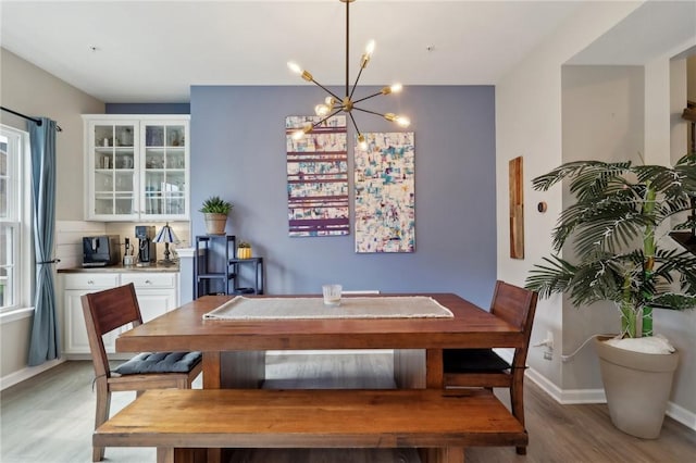dining area with light wood finished floors, a chandelier, and baseboards