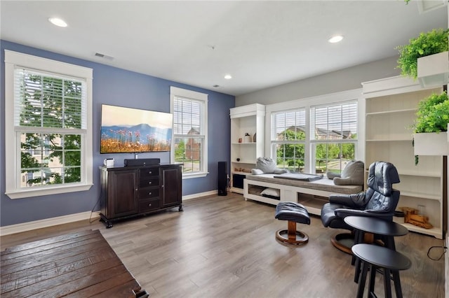 living area with light wood-type flooring, baseboards, healthy amount of natural light, and recessed lighting