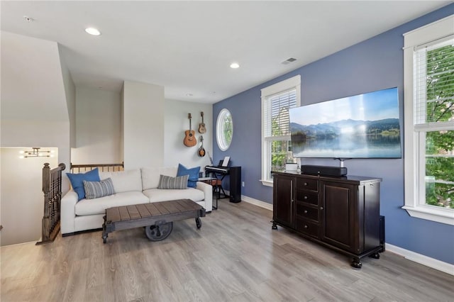 living area with light wood-type flooring, healthy amount of natural light, recessed lighting, and baseboards