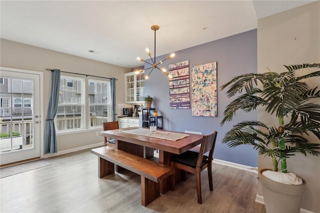 dining space with light wood-style floors, a chandelier, and baseboards