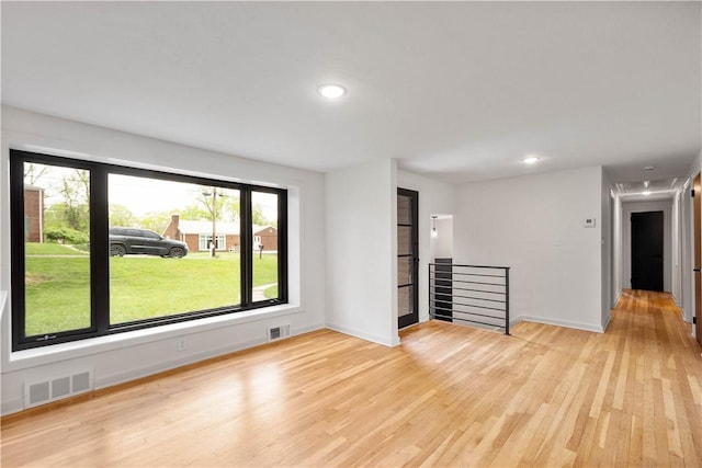 unfurnished room with light wood-style floors, healthy amount of natural light, baseboards, recessed lighting, and attic access