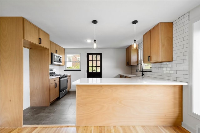 kitchen with stainless steel appliances, a peninsula, backsplash, and light countertops